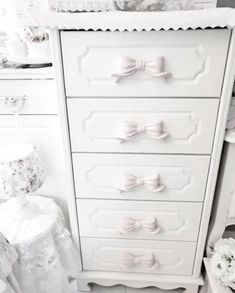 a white dresser with lots of drawers and bows on it