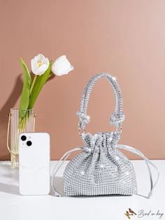 a white purse sitting on top of a table next to a vase filled with flowers