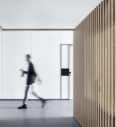 a blurry photo of a man walking in an office building with wood slats on the walls