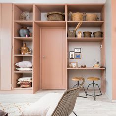 a room with shelves, stools and baskets on the wall next to a bed