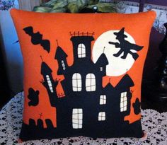 an orange pillow with black houses and bats on it