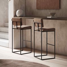 two modern bar stools in front of a counter with a vase on the side