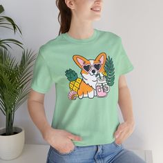 Introducing our Summer Corgi Unisex Graphic Tee – a must-have addition to your warm-weather wardrobe that combines adorable corgi charm with the laid-back vibes of summer! This tee isn't just clothing; it's a fun and stylish way to celebrate your love for these delightful pups and the sunny season. Crafted for both men and women who adore corgis, this tee is perfect for adding a touch of whimsy to your summer look, whether you're lounging at the beach or soaking up the sun by the pool. Featuring a playful corgi graphic and made from high-quality materials for comfort and durability, this tee is sure to become a favorite in your collection. Whether you're a proud corgi lover or searching for the perfect gift for a fellow dog enthusiast, our Summer Corgi Unisex Graphic Tee is guaranteed to b Cute Cotton Tops With Dog Print, Relaxed Fit Short Sleeve Tops With Dog Print, Casual Crew Neck Tops With Dog Print, Cute Cotton Top With Dog Print, Short Sleeve Dog Print Top For Summer, Cotton Crew Neck Top With Dog Print, Cute Crew Neck Top With Dog Print, Cute Dog Print Cotton Top, Cute Short Sleeve Tops With Dog Print