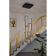 a modern chandelier hanging from the ceiling in front of a stair case with paintings on the wall