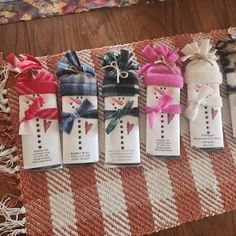 five small snowmen wrapped in pink and white ribbon on a tablecloth with other decorations