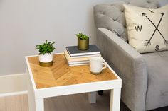 a coffee table with two books on it next to a couch and a potted plant