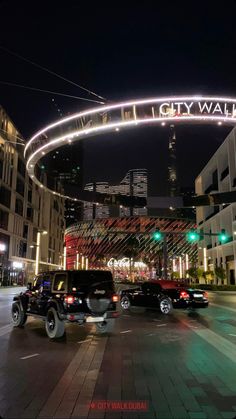 the city wall sign is lit up at night in front of some buildings and cars