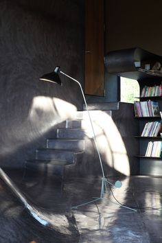 a floor lamp sitting on top of a cement floor next to a bookshelf