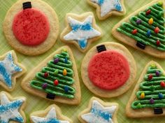 christmas cookies decorated with icing and decorations on a green tableclothed cloth,