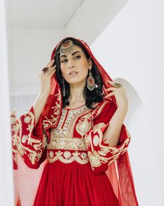 a woman in a red and gold dress is holding her head up to her ear