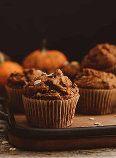 some muffins sitting on top of a wooden tray next to other pumpkins