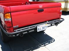 the back end of a red truck parked in front of a yellow and white bus