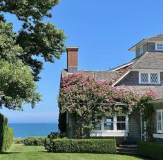 the house is next to the ocean and has pink flowers on it