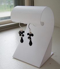 a pair of black and white earrings sitting on top of a table next to a window