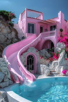 a pink house with a water slide in the pool and flowers growing on the rocks