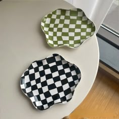 two black and white checkered plates sitting on a table next to a glass window