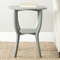 a table with a book on top of it in front of a white chair and rug