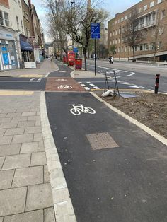 a bike lane on the side of a street with buildings in the background and signs indicating where to go