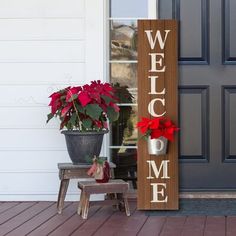 a welcome sign with poinsettis and a potted plant on the porch