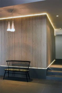 a room with a chair and some lights on the wall next to stairs that are lit up