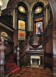 an ornate staircase with stained glass windows and wood paneling on the walls is pictured in this image