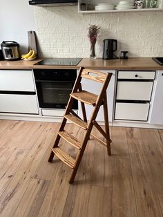 a wooden step stool sitting on top of a hard wood floor next to a stove