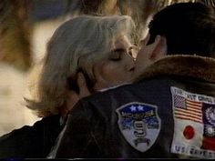 a man and woman kissing each other with an american flag on the back of their jacket