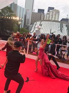 two people are dancing on the red carpet in front of a large group of people