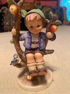 a figurine sitting on top of a tree branch with an apple in it