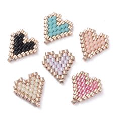 four pieces of beaded heart brooches in various colors and sizes on a white background