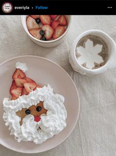 a plate with strawberries and whipped cream on it next to a cup of coffee