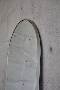 an oval shaped mirror mounted to the side of a wall next to a cement wall