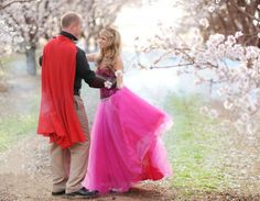 a man and woman in formal wear standing next to each other under cherry blossom trees