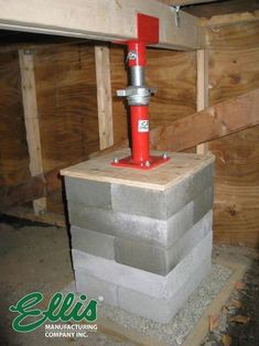 a fire hydrant sitting on top of a block of cement next to a wooden wall