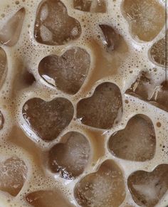 heart shaped ice cubes are in a bowl of hot chocolate liquid with water on the side