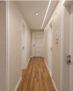 an empty hallway with white walls and wooden floors