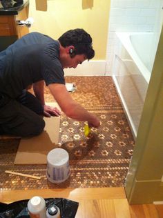 a man kneeling down on the floor with some paint in front of him and an open box