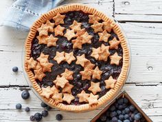 a pie with blueberries and stars on it next to a box of cookies,