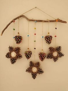 a clock made out of pine cones hanging from a branch with beads and chains attached to it