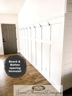 an entryway with white paneling and coat hooks on the wall next to a wooden floor