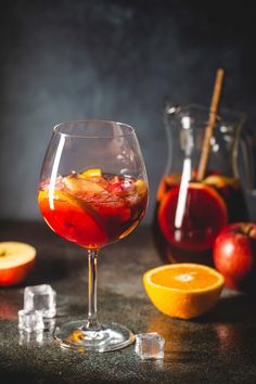 a glass filled with liquid next to sliced oranges and apples