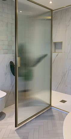 a glass shower door in a bathroom with white tile flooring and wall tiles on the walls