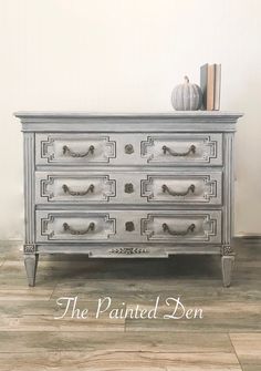 an old dresser painted in silver and white with the words, the painted den on it