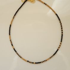 In this Surfer Necklace, I used black and matte gold color seed beads. I also used Men's Beaded Necklace, Stainless Steel Jewelry wire, 24K Gold Plated Extension Chain, 24K Gold Plated Lobster Claw. Each Seed Bead Necklace has a 1 inch extension chain. You can use this Black Beaded Necklace with any outfit. Black And Gold Beaded Necklace, Black Heishi Beads Jewelry, Handmade Black Heishi Beads, Black Beaded Necklace With Gold Beads As Gift, Black Necklaces With Round Gold Beads, Handmade Minimalist Gold Beads, Black Heishi Beads Necklace For Gift, Minimalist Gold Beaded Necklace With Black Beads, Minimalist Gold Necklace With Black Beads