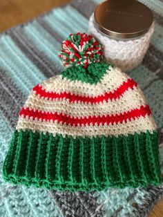 a knitted hat sitting on top of a table next to a canister filled with yarn