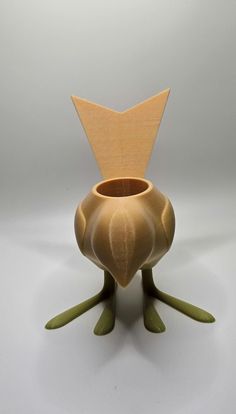 a small vase with two legs and a wooden bird head on the front, sitting upright