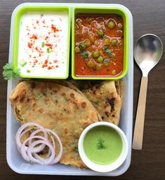 a tray with some food on it and a spoon next to it, sitting on a table