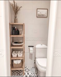 a white toilet sitting in a bathroom next to a wooden shelf filled with containers and baskets