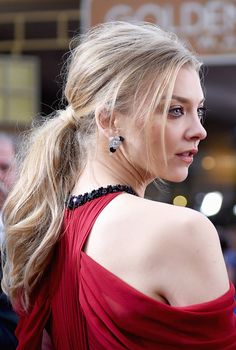 a woman in a red dress is looking off to the side with her hair pulled back