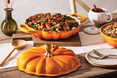 a table topped with orange dishes filled with food next to plates and utensils